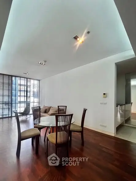 Spacious modern dining area with wooden flooring and large windows in a luxury apartment.