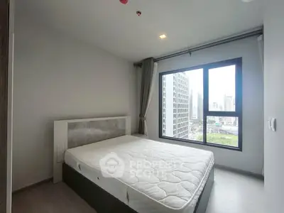 Modern bedroom with large window offering city view in high-rise apartment.