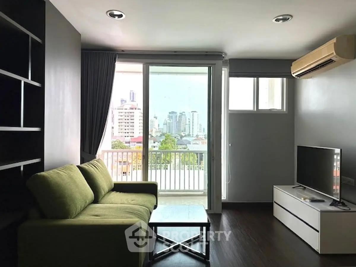Modern living room with green sofa, city view, and balcony access.