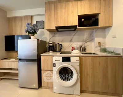 Modern kitchen with wooden cabinets, washing machine, and stainless steel appliances in a cozy apartment.