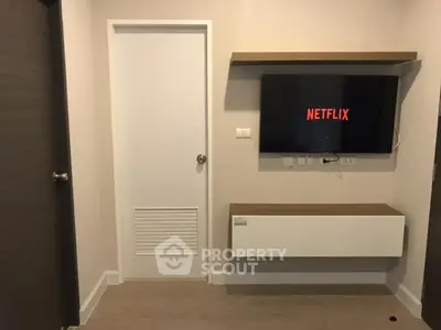Modern living room with wall-mounted TV and sleek storage unit.