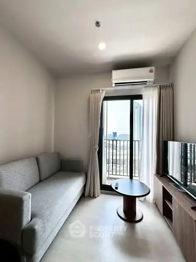 Modern living room with balcony view, featuring a cozy sofa and sleek TV setup.