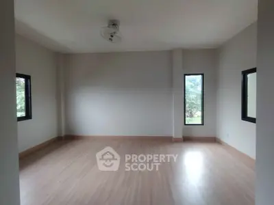 Spacious empty room with large windows and wooden flooring, ideal for customization.