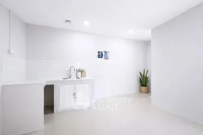 Minimalist kitchen with white cabinetry and sleek tile backsplash in modern apartment.