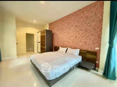 Spacious bedroom with brick accent wall and modern furnishings