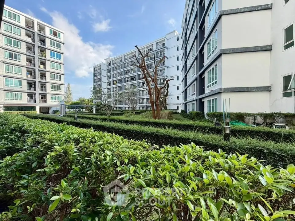 Modern apartment buildings with lush green garden and clear blue sky