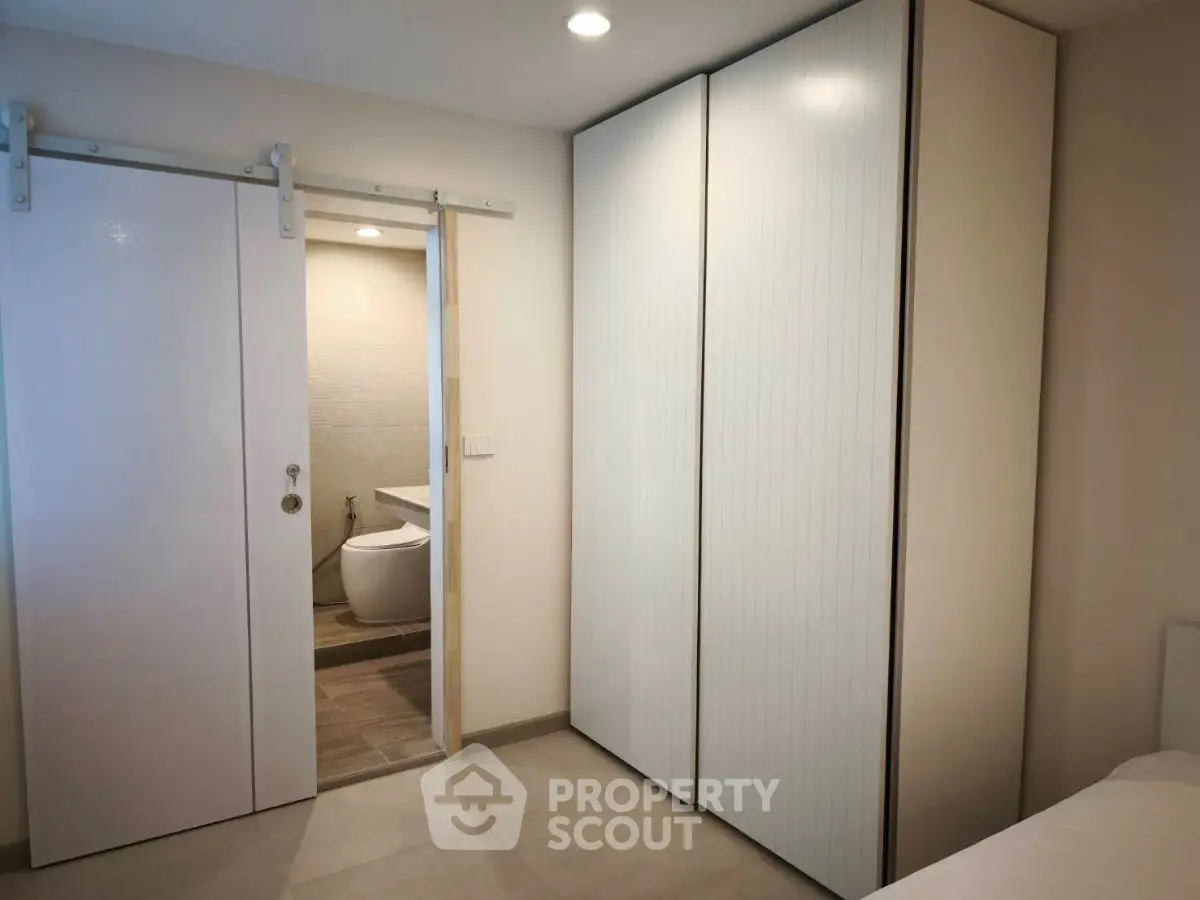 Modern bedroom with sliding door leading to a sleek bathroom