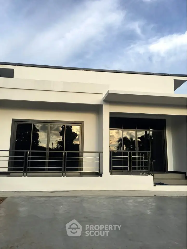 Modern minimalist white house exterior with large windows and sleek railing.