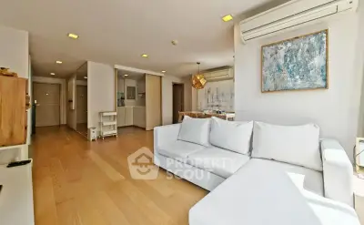 Spacious living room with modern decor and natural light, featuring a comfortable white sofa and stylish artwork.