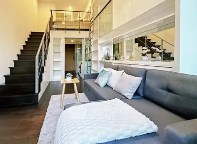Modern loft-style living room with sleek staircase and cozy seating area.