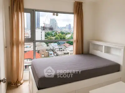 Cozy bedroom with large window offering stunning city view in modern apartment.