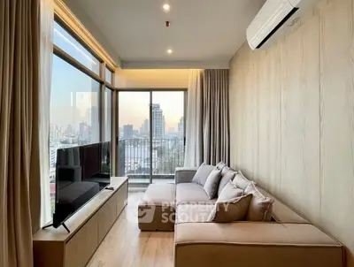Modern living room with large windows and city view, featuring a cozy sofa and sleek TV setup.