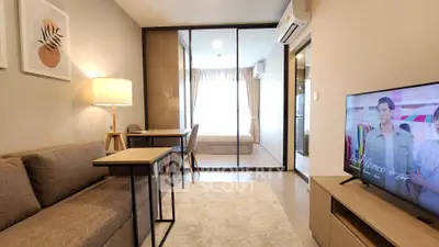 Modern living room with cozy sofa, stylish decor, and view into a bright bedroom through glass doors.