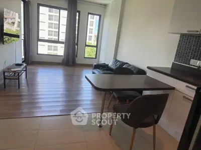 Modern open-plan living room with sleek kitchen and large windows in urban apartment.