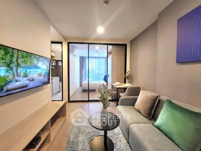 Modern living room with stylish decor and open view to bedroom, featuring cozy seating and wall-mounted TV.