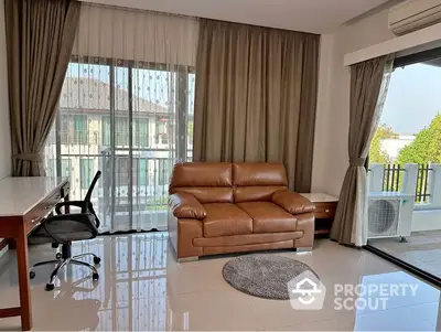 Spacious and sunlit living room with gleaming tiled floors, luxurious leather sofa, and floor-to-ceiling windows draped in elegant curtains.