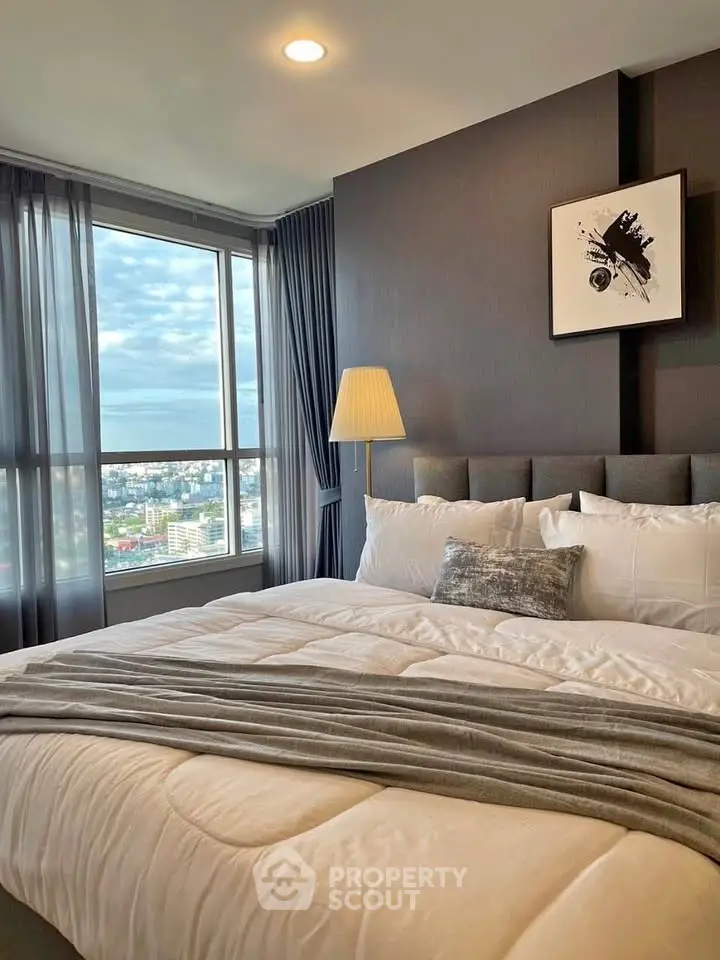 Luxurious bedroom with large window offering stunning city views, modern decor, and cozy bedding.