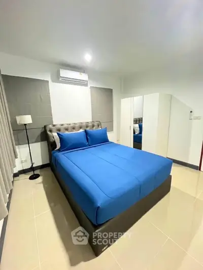 Modern bedroom with blue bedding and sleek design, featuring a comfortable bed and ample storage.