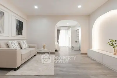 Elegant modern living room with neutral tones and stylish decor, leading to a bright bedroom.