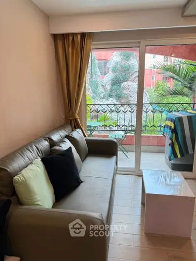 Cozy living room with balcony view, featuring a comfortable sofa and modern decor.