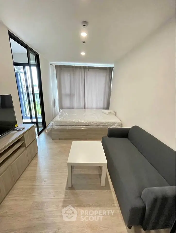 Modern studio apartment with cozy living area and large window view.