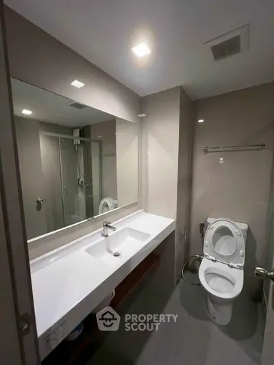 Modern bathroom with sleek fixtures and spacious shower area in contemporary apartment.
