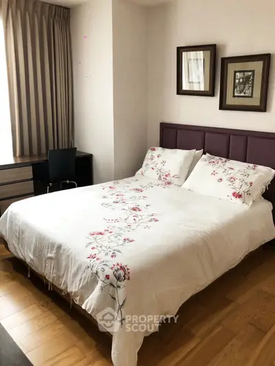 Cozy bedroom with elegant decor and natural light, featuring a stylish bed and wooden flooring.