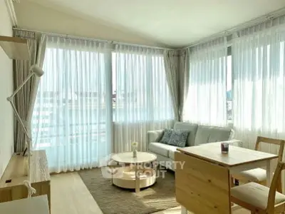 Bright and airy living room with modern furniture and large windows in a corner unit apartment.