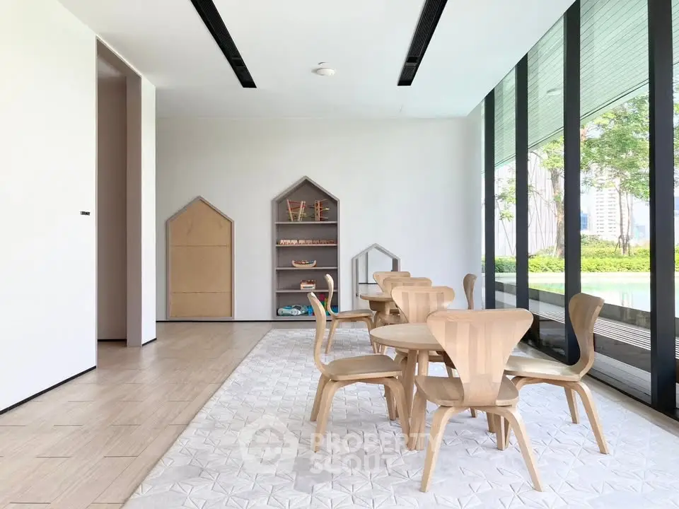 Modern communal area with wooden furniture and large windows overlooking greenery.