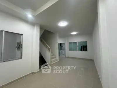 Spacious modern interior with sleek staircase and tiled flooring, ideal for contemporary living.