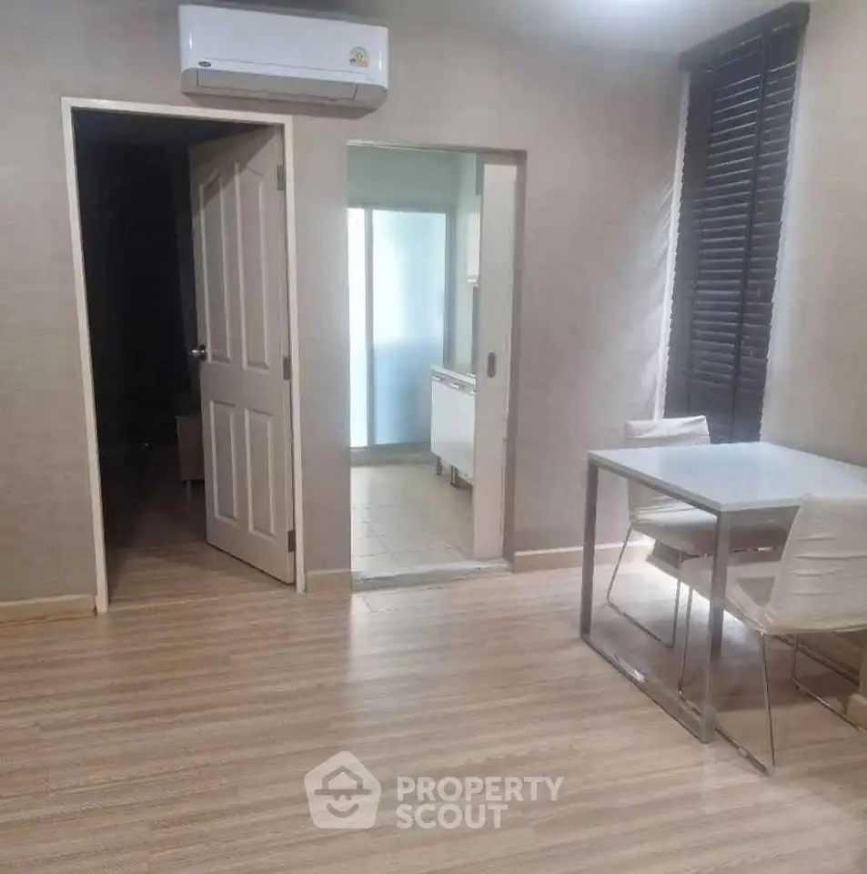Modern apartment interior with sleek dining area and air conditioning, featuring wooden flooring and neutral tones.