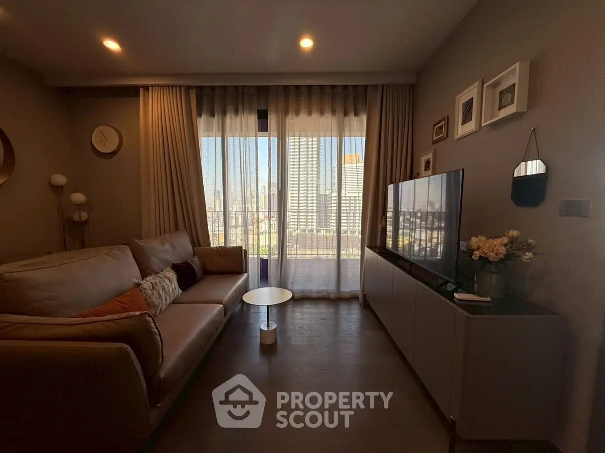 Modern living room with cozy sofa, large TV, and city view through sheer curtains.