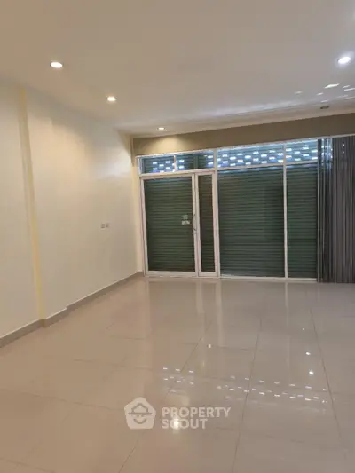 Spacious empty room with large windows and tiled flooring, ideal for customization.