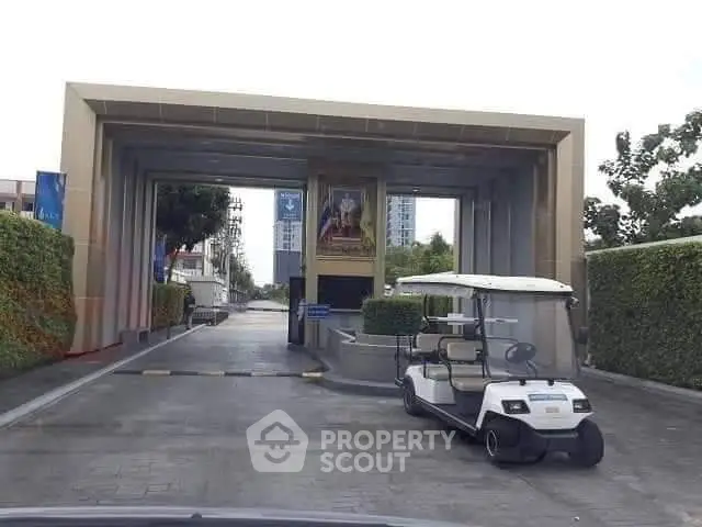 Modern gated entrance with golf cart and lush greenery