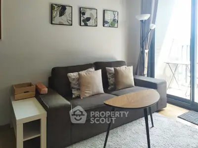 Cozy living room with modern sofa, stylish decor, and balcony access for urban living.