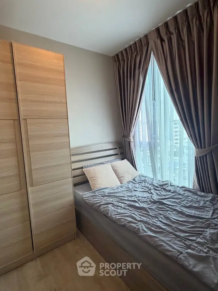 Cozy bedroom with modern wooden furniture and large window with city view.