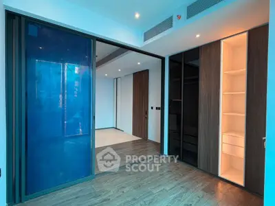 Modern interior with sleek wooden flooring and built-in shelving, featuring sliding glass doors for a spacious feel.