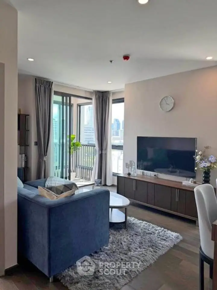 Modern living room with city view, featuring stylish furniture and large windows for natural light.