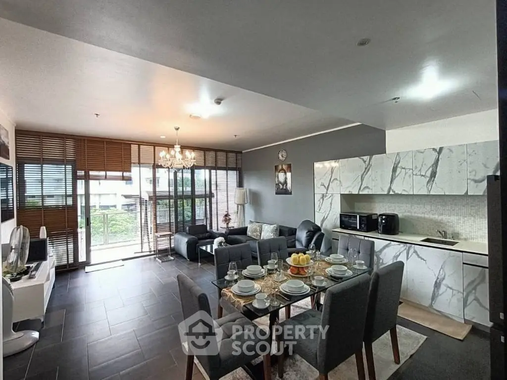 Modern open-plan living room with stylish kitchen and dining area, featuring elegant decor and natural light.