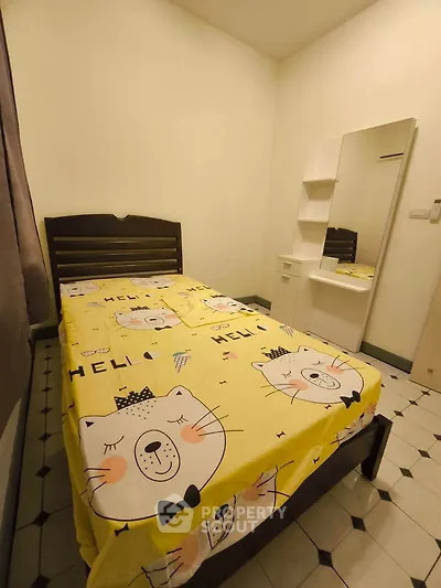 Cozy bedroom with charming cat-themed bedding and a sleek vanity mirror.