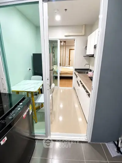 Modern apartment with sleek kitchen and dining area, featuring open layout and stylish design.