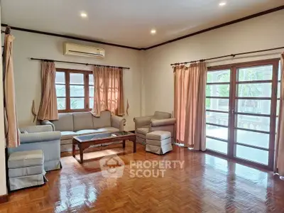 Spacious living room with parquet flooring and large windows for natural light.