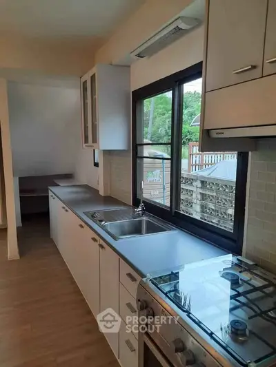 Modern kitchen with sleek cabinetry, stainless steel appliances, and large window offering natural light.