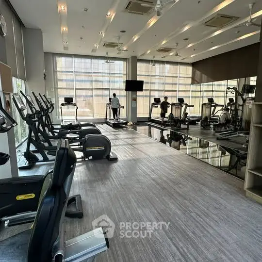 Spacious modern gym with state-of-the-art equipment and large windows.