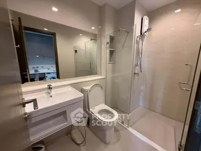 Modern bathroom with sleek fixtures and glass shower enclosure in a contemporary apartment.