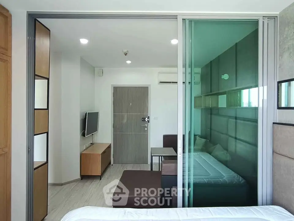 Modern studio apartment with sliding glass partition and sleek interior design.