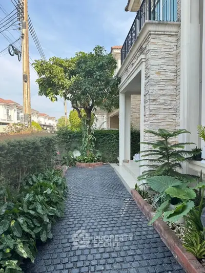 Charming exterior view of a modern home with lush garden and stone pathway.