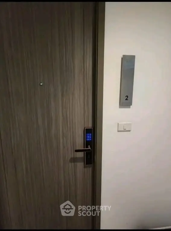Modern apartment door with digital lock and room number sign, showcasing secure entry features.