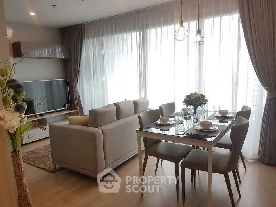 Modern living room with dining area, featuring elegant decor and large windows for natural light.
