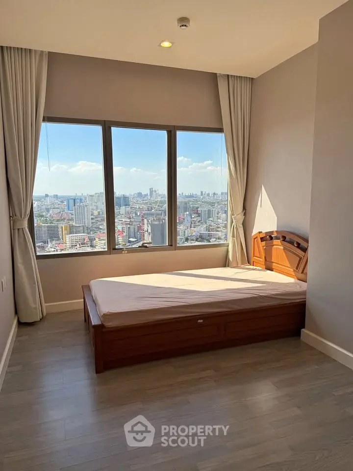Spacious bedroom with stunning city view and large windows in modern apartment.